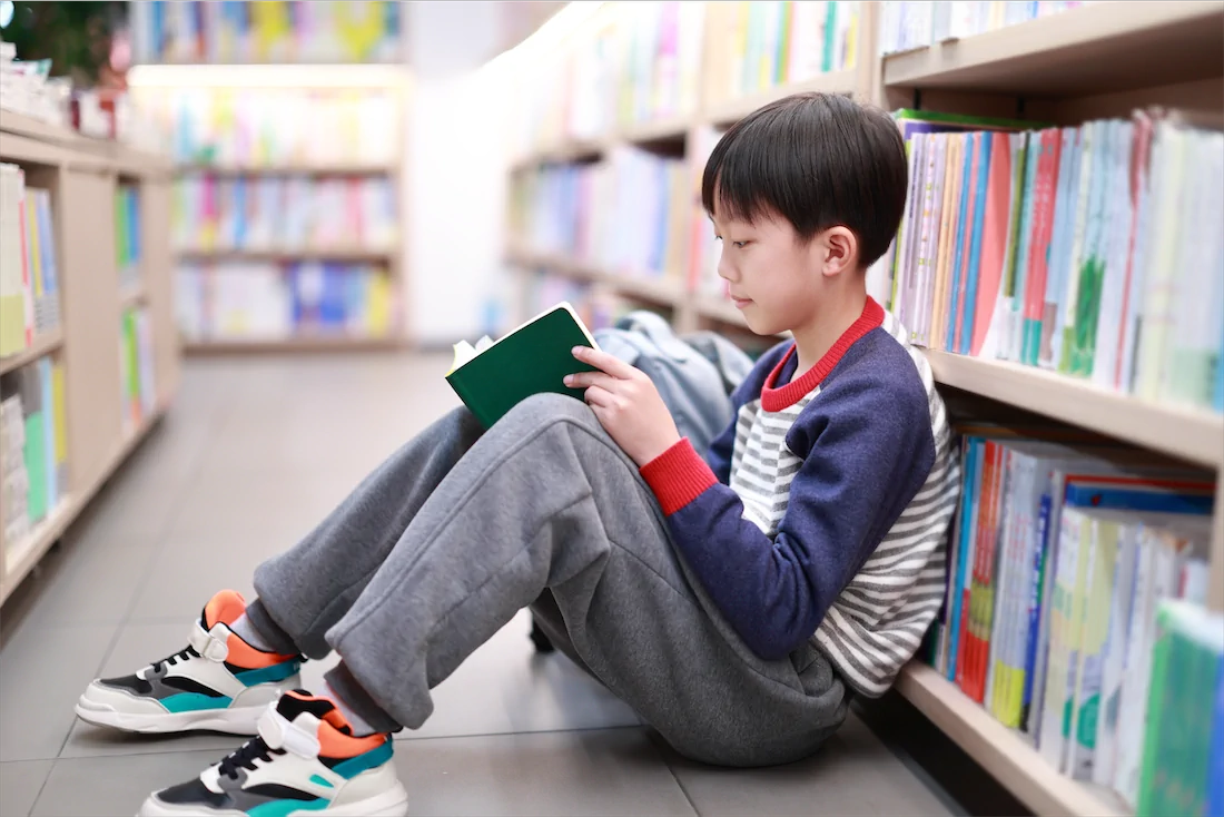 Boy reading a traditional book in a library